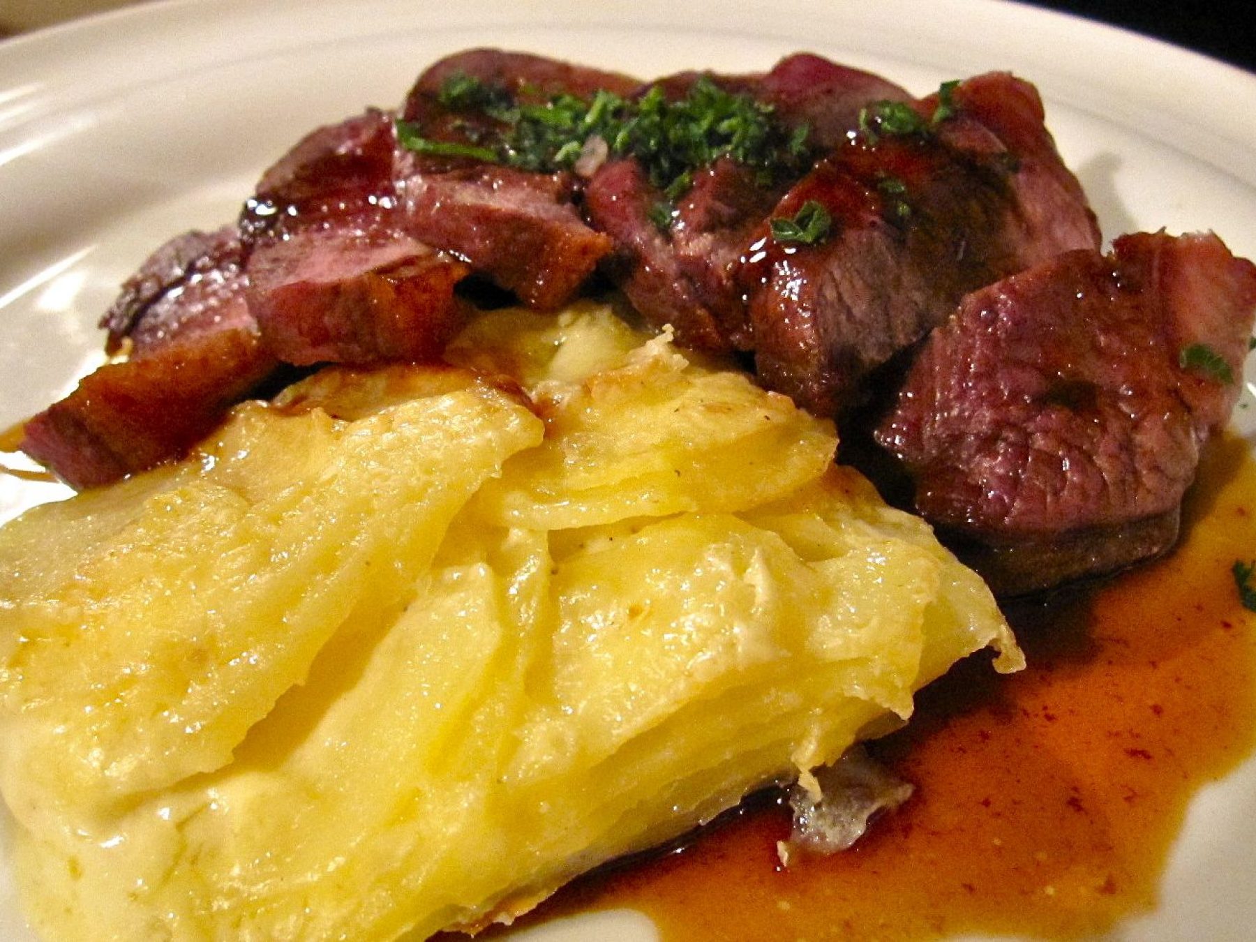 Magret de pato con puré de berenjena y queso de cabra y crujiente de parmesano y gratén de patata con bacon.